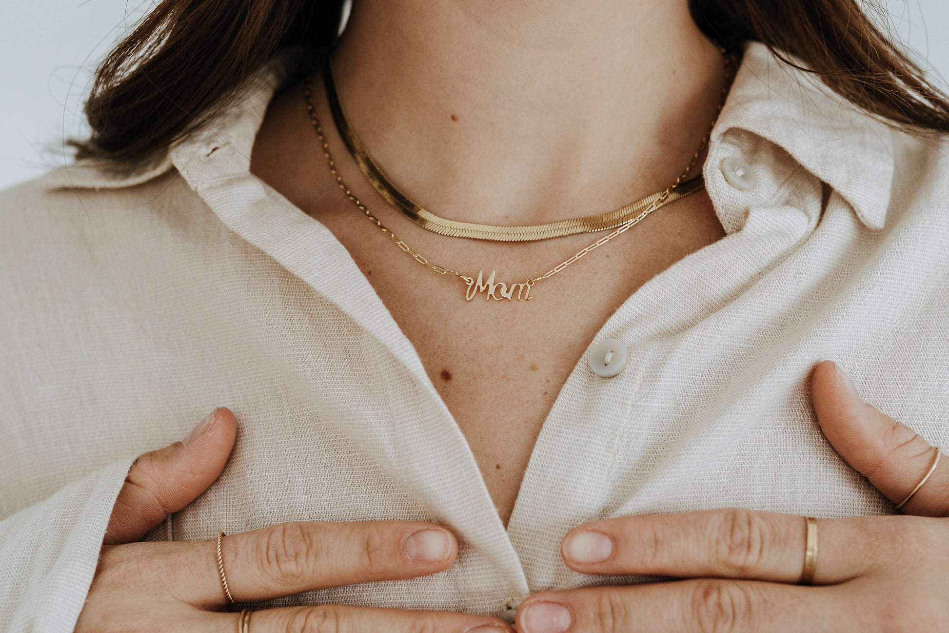 Personalized style Mom necklace in gold worn layered with a gold herringbone chain.