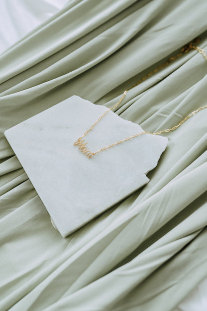 Close-up of gold Mom pendant necklace featuring elegant cursive lettering.