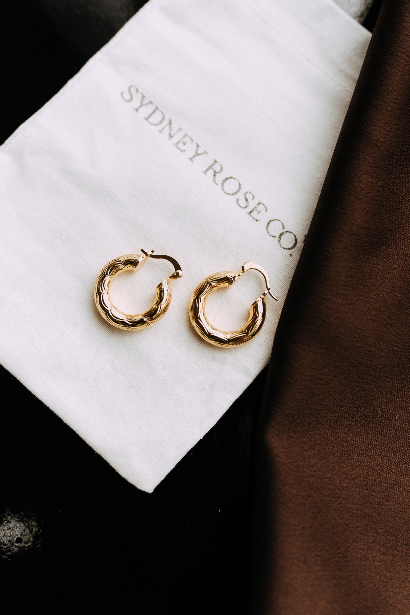Camellia 18k gold filled textured hoop earrings displayed on Sydney Rose Co. jewelry pouch