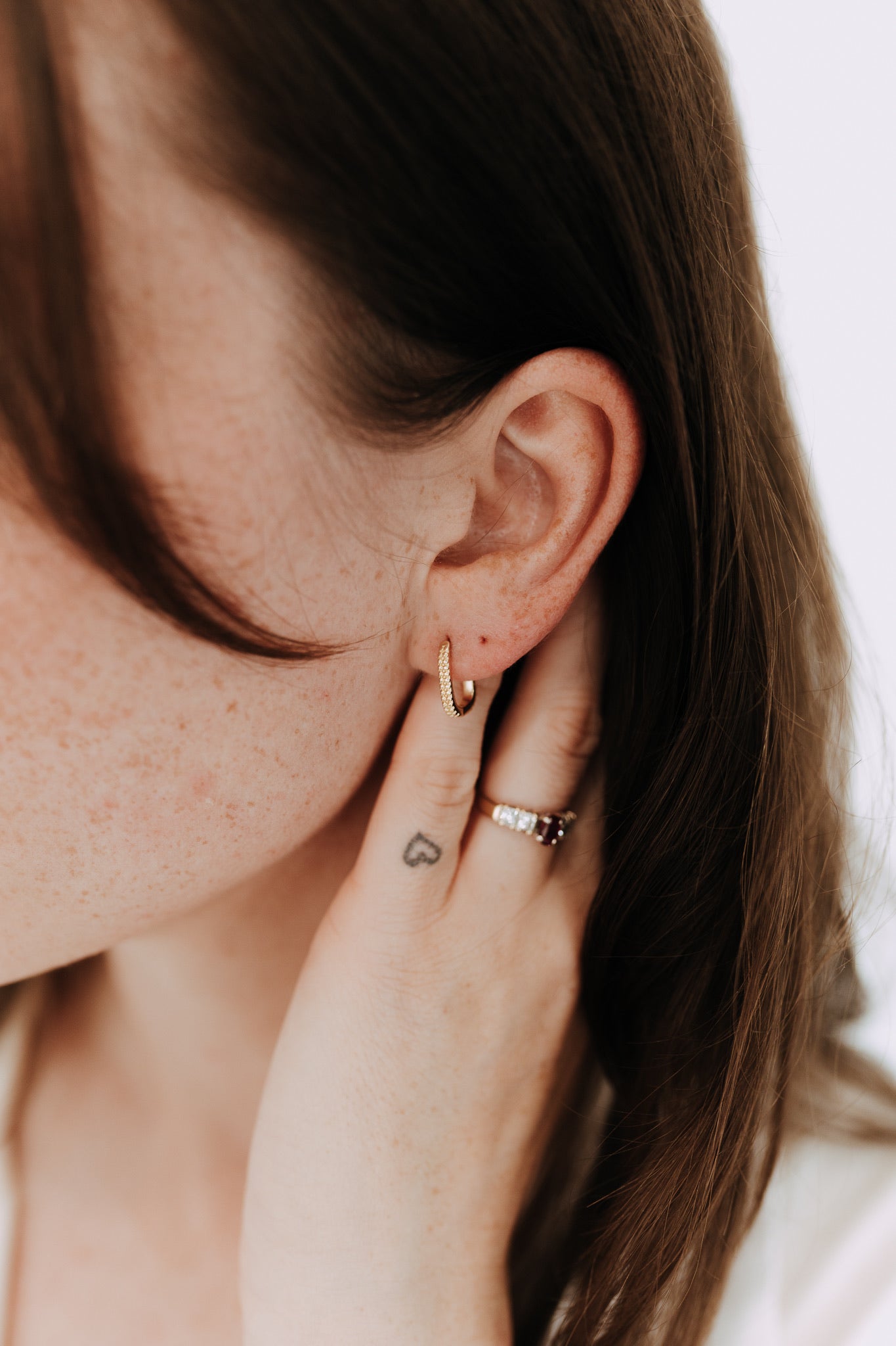 Side profile showing textured geometric gold hoop earrings