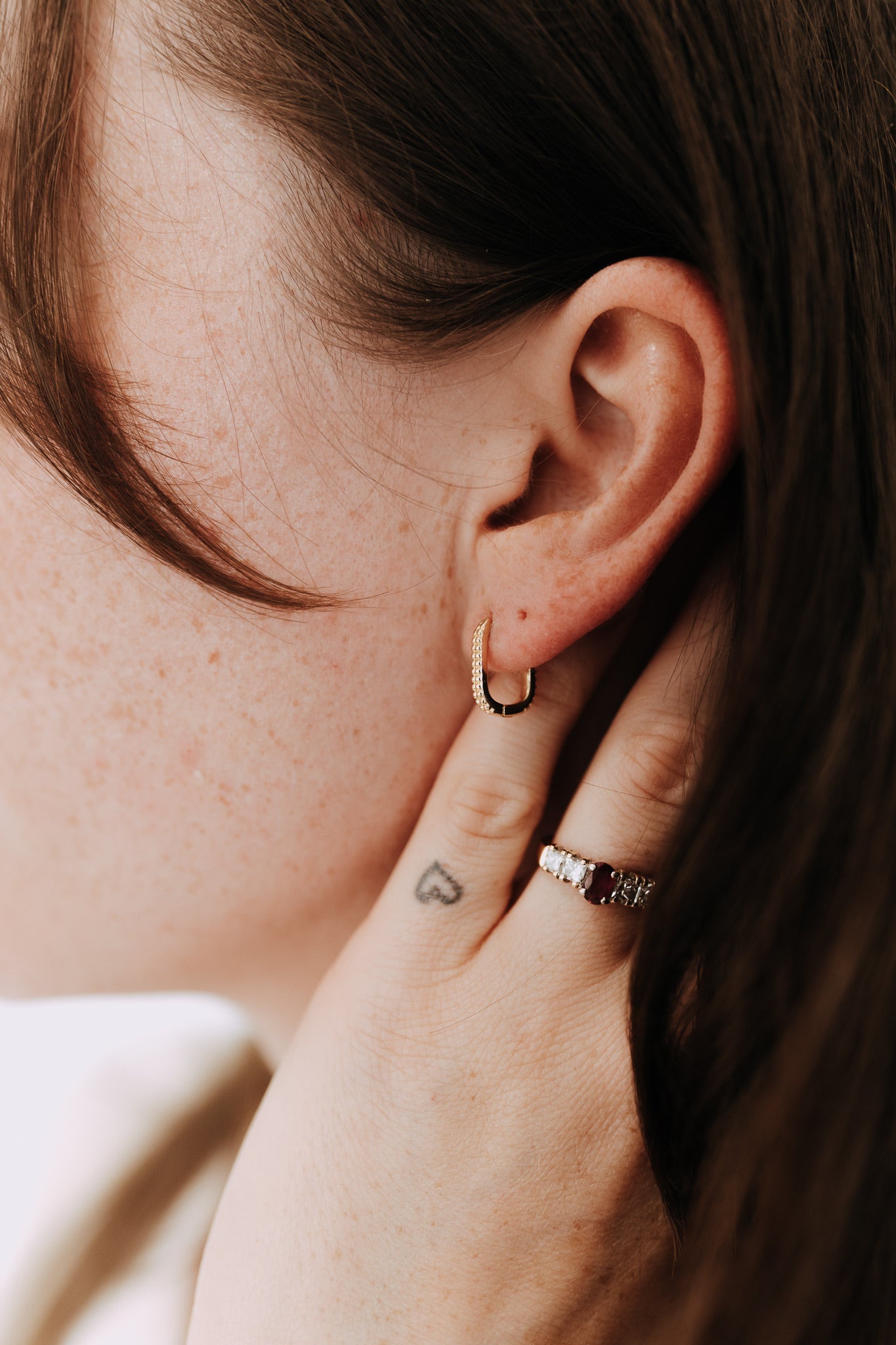 Close-up of textured geometric rectangle hoop earrings in gold