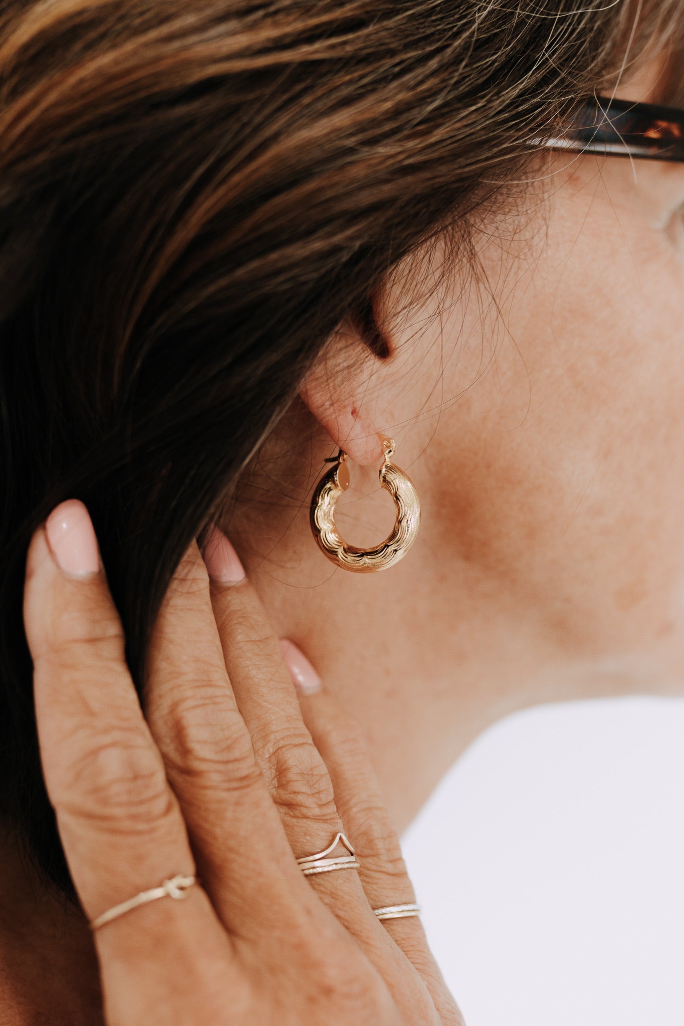 Side profile of model wearing Camellia gold filled textured hoop earrings