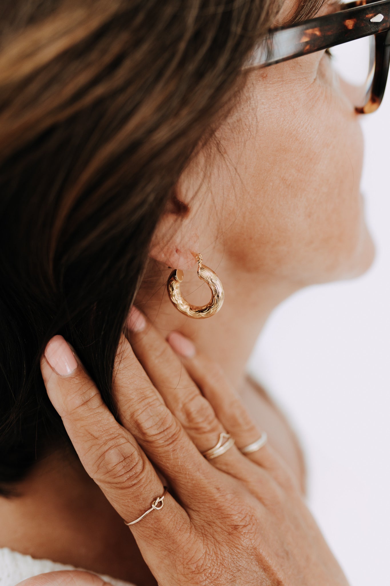 Close-up of textured gold filled hoop earrings on model