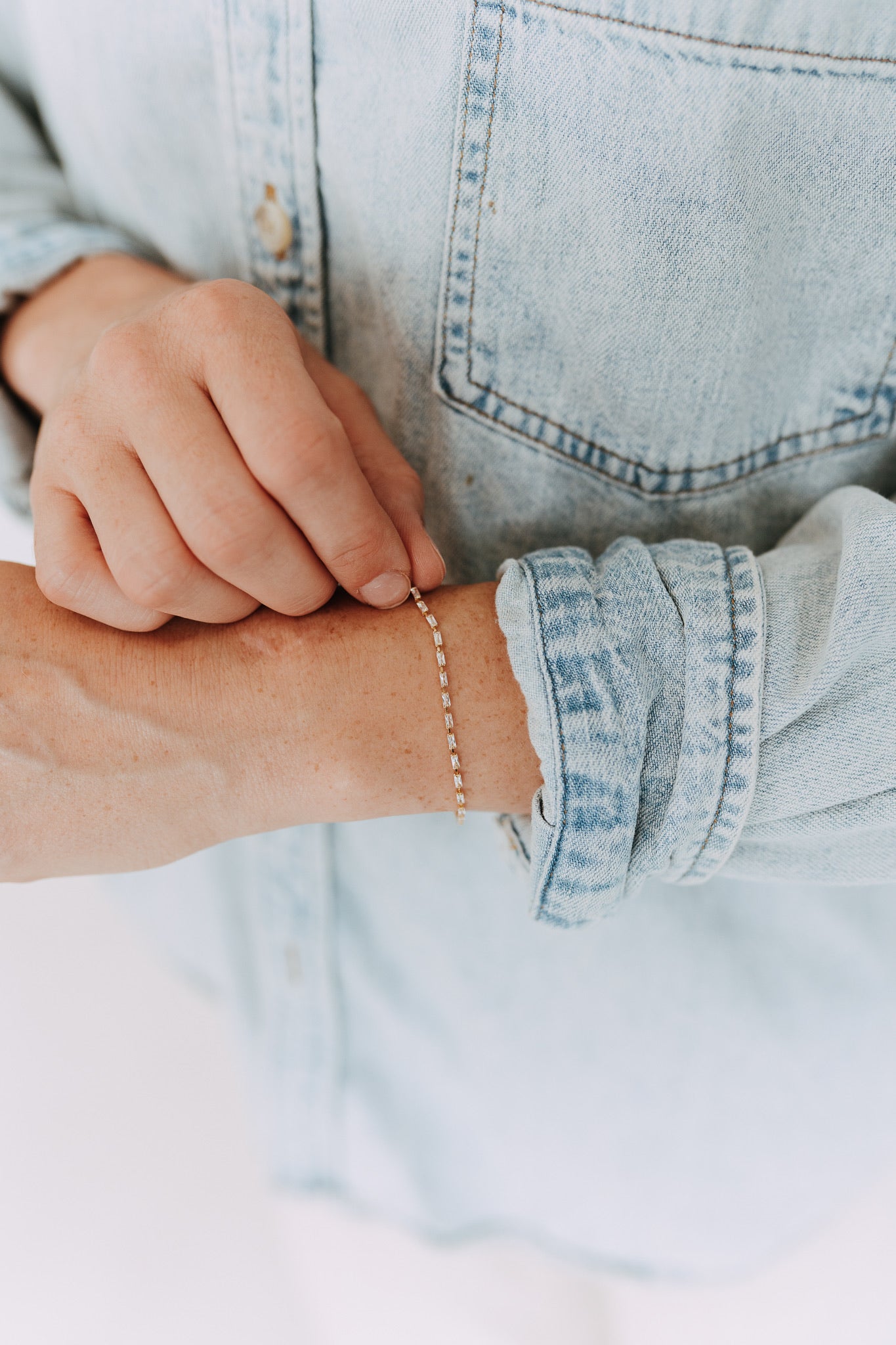Woman wearing a gold filled baguette tennis bracelet with denim shirt