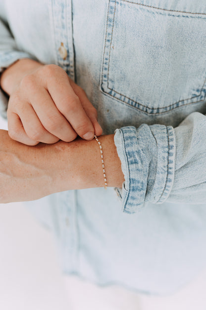 Woman wearing a gold filled baguette tennis bracelet with denim shirt