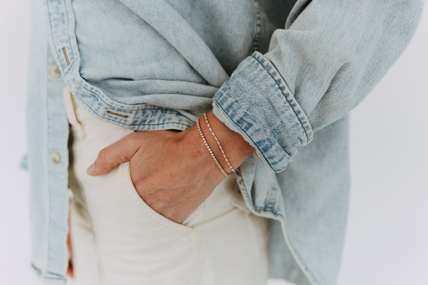 Gold baguette tennis bracelet styled with layered bracelets