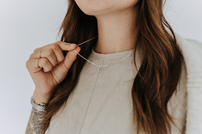 Dainty sterling silver heart pendant necklace layered on a casual everyday outfit