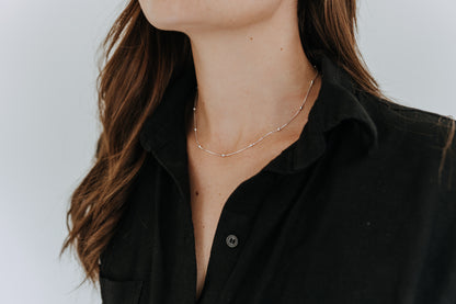 Close-up of dainty sterling silver satellite necklace featuring evenly spaced silver beads.