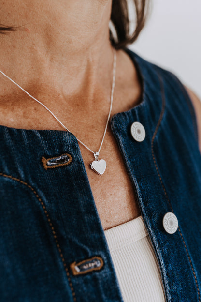 Heart-shaped sterling silver locket necklace on a delicate box chain.
