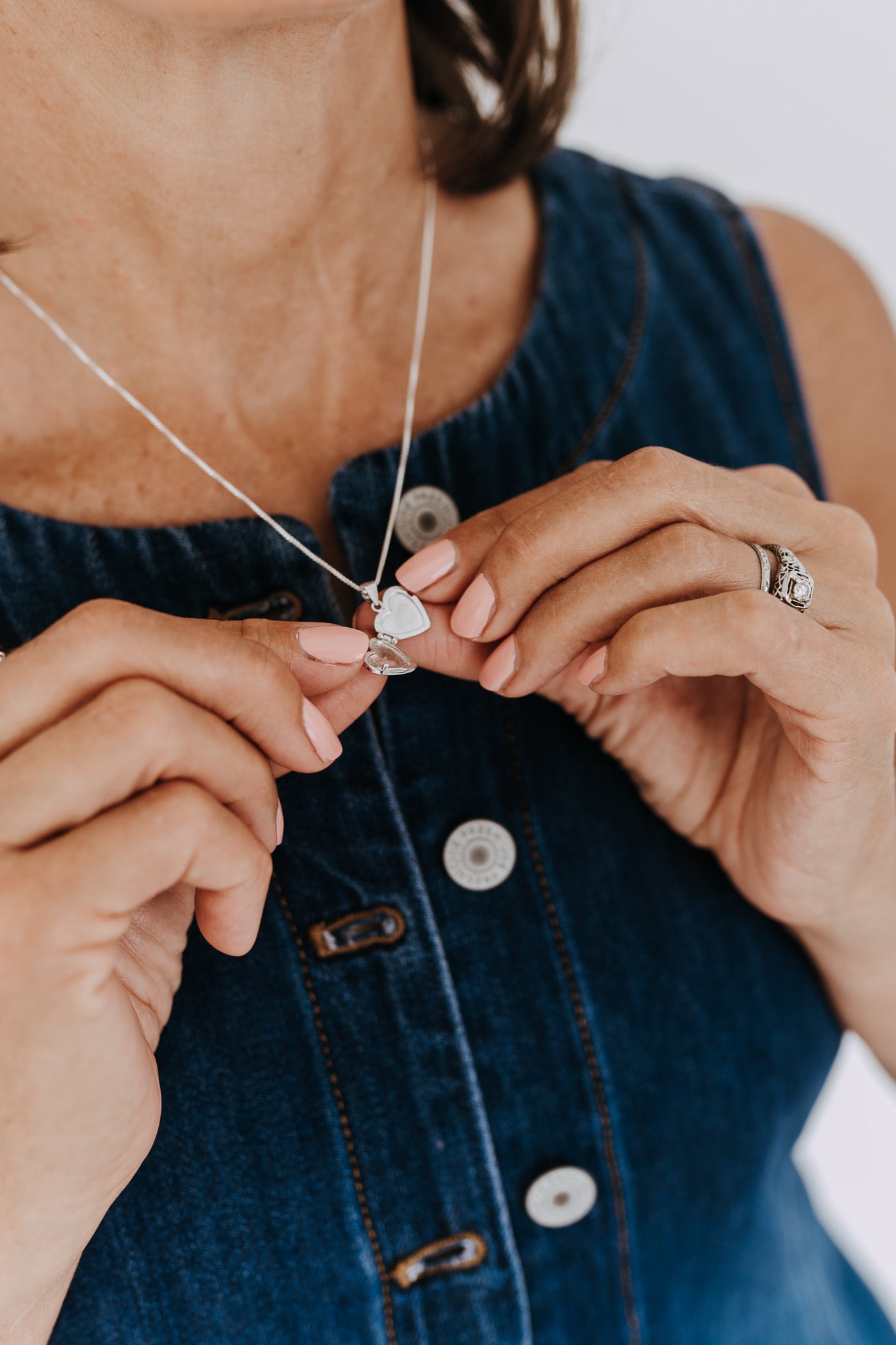 Open heart locket necklace in sterling silver held between hands.