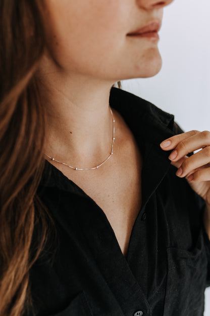 Sterling silver satellite chain necklace with delicate 3mm beads worn on model.