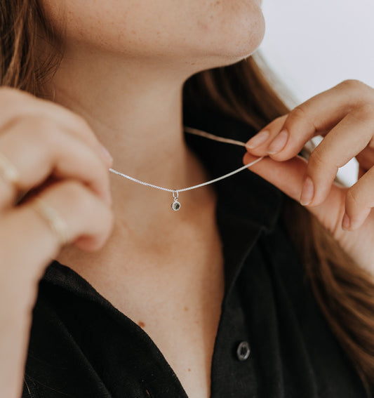 Close-up of sterling silver custom birthstone necklace on a fine chain.