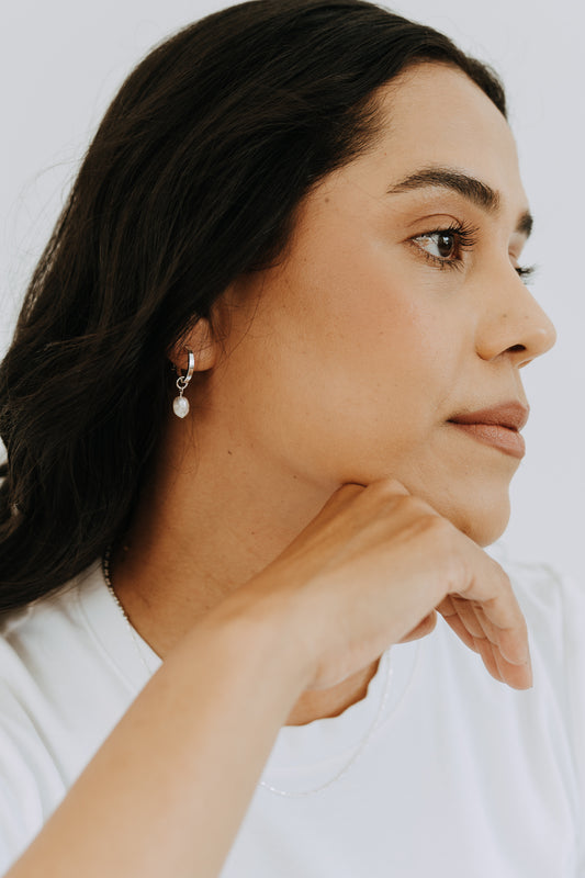Woman wearing sterling silver pearl drop hoop earrings with genuine freshwater pearl charms.