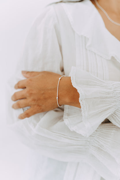 Minimal sterling silver Orbit bracelet styled with a white blouse.