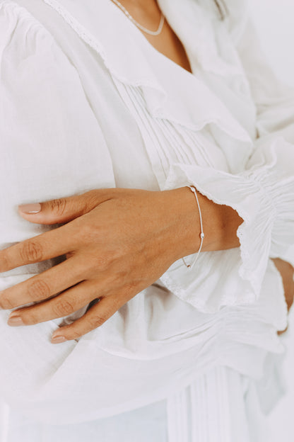 Close-up of a sterling silver floating bead bracelet on wrist.