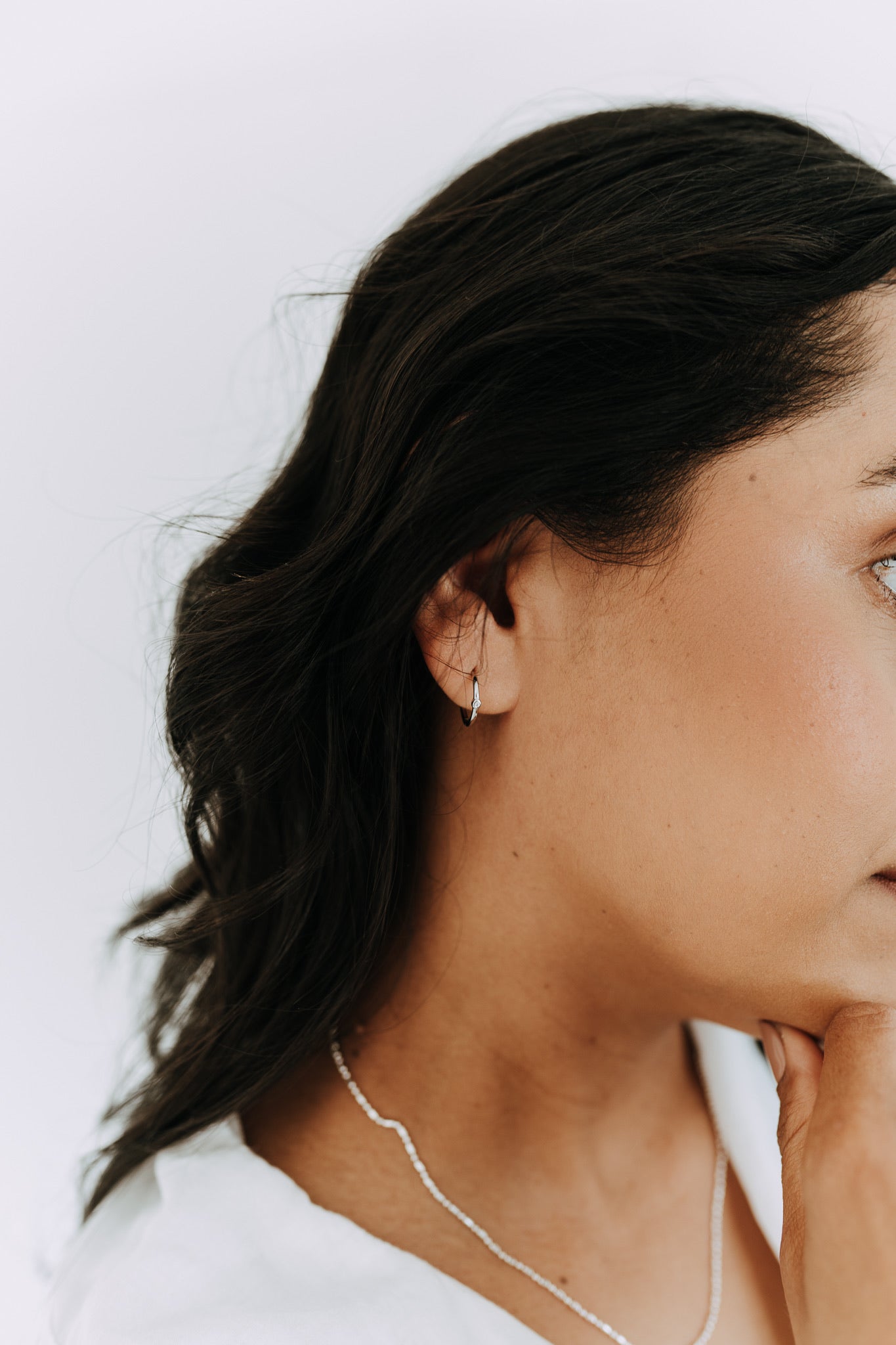 Lightweight sterling silver huggie earrings with a single cubic zirconia stone for everyday wear.