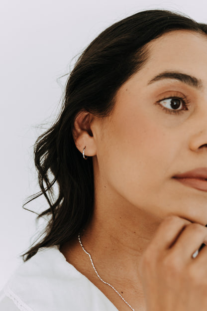 Minimalist sterling silver hoop earrings featuring a subtle cubic zirconia accent.