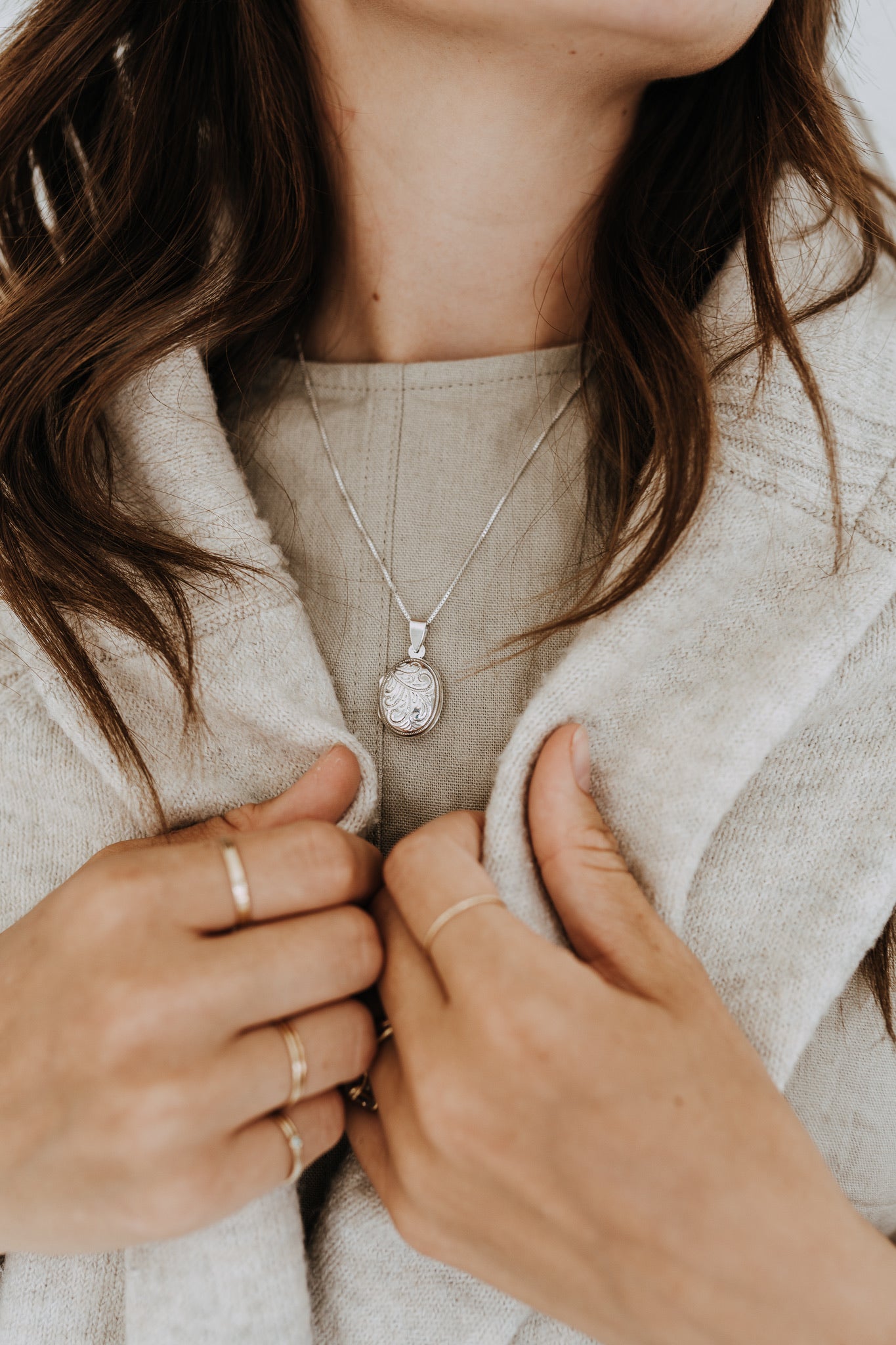 Sterling silver oval locket necklace styled with a cozy cream cardigan for everyday wear.