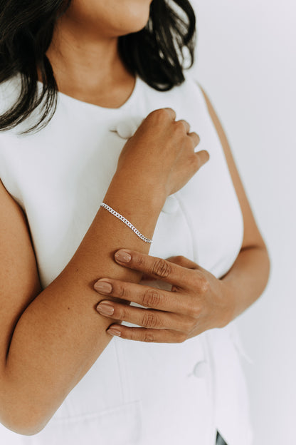 Women's 3.5mm sterling silver curb bracelet styled with a white top.