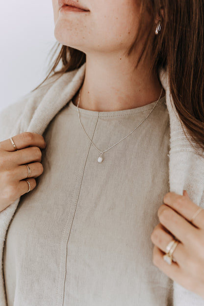 Woman wearing a sterling silver freshwater pearl drop necklace on a delicate box chain.