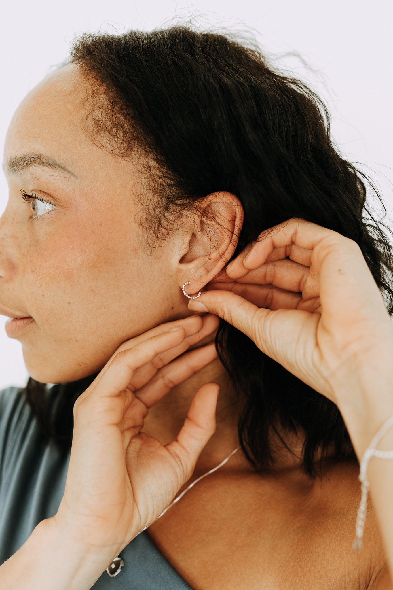 Model adjusting Juniper sterling silver huggie hoops with click closure.