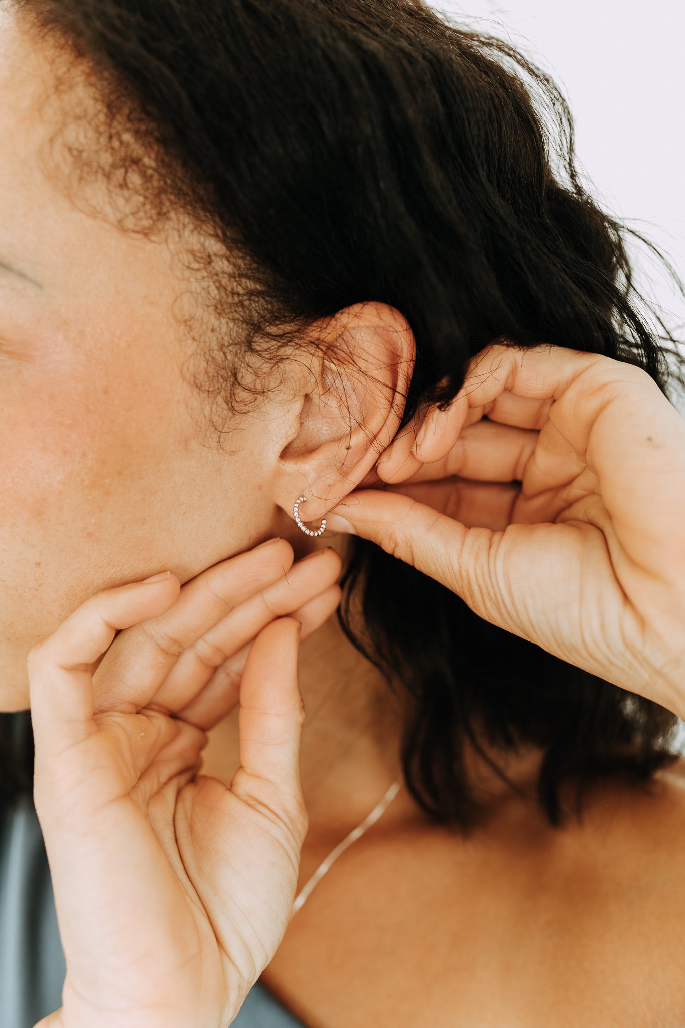 Close-up of Juniper sterling silver huggie hoops with textured beaded design.