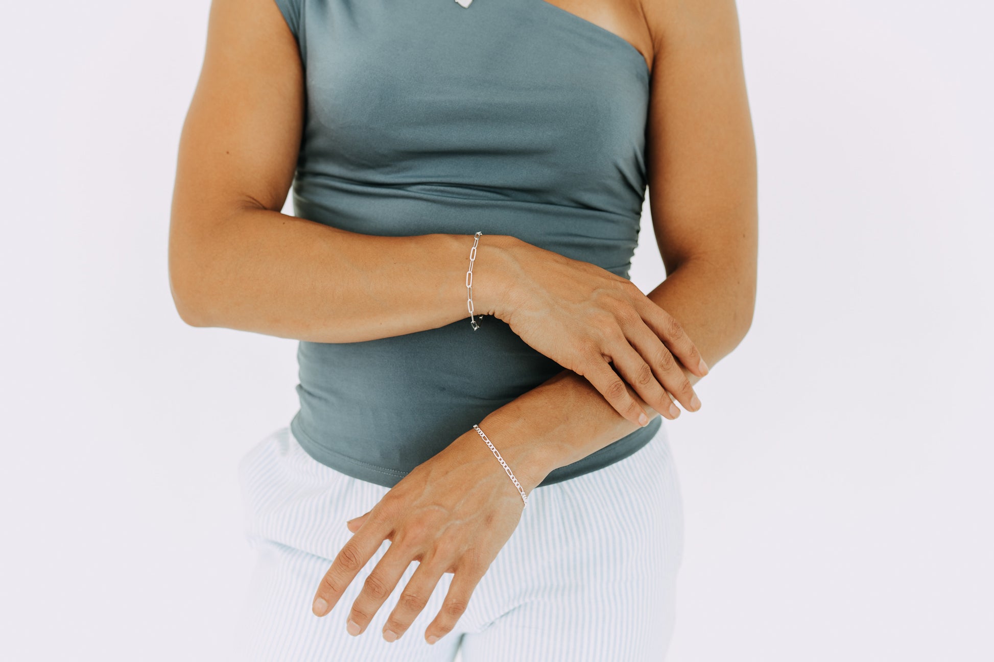 Woman wearing a 3mm sterling silver Figaro bracelet on wrist with matching silver jewelry