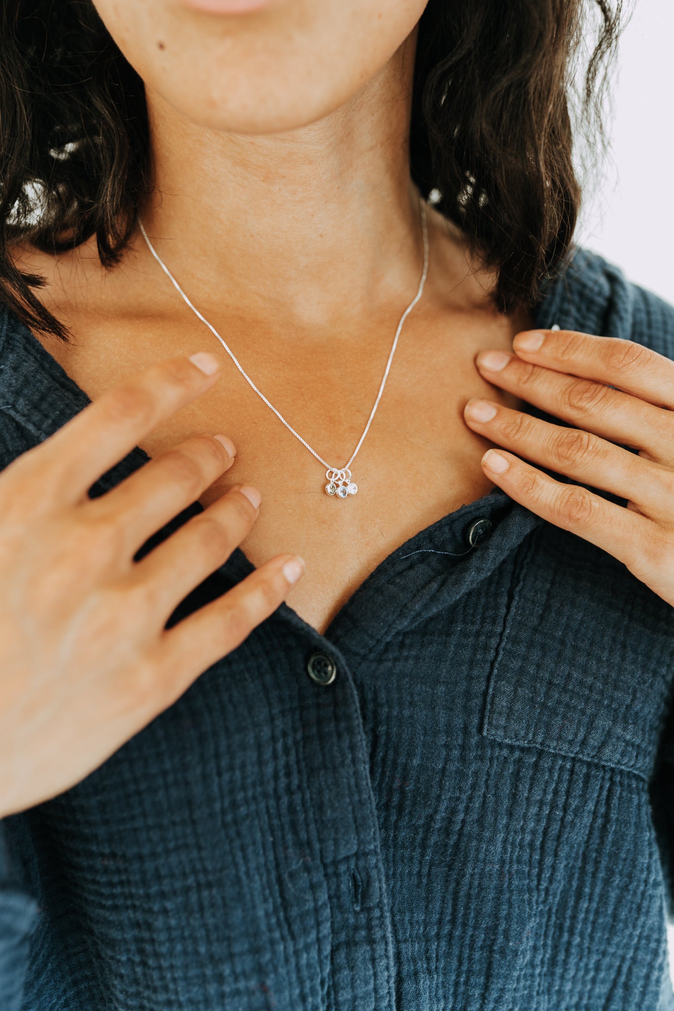 Woman wearing a sterling silver necklace with personalized birthstone charms.