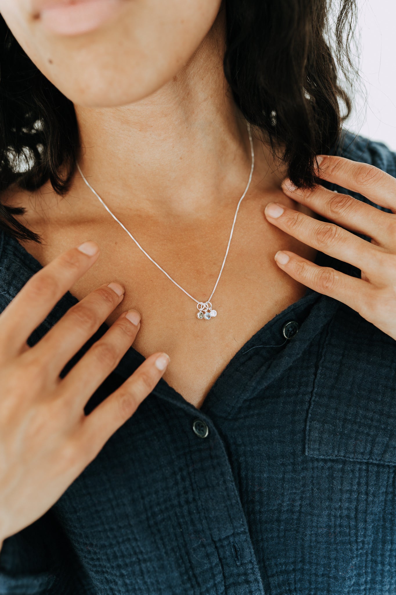 Woman wearing a sterling silver necklace with personalized birthstone charms.