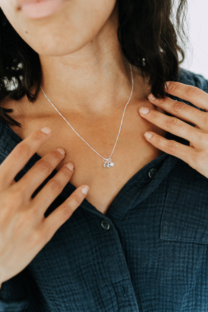 Woman wearing a sterling silver necklace with personalized birthstone charms.