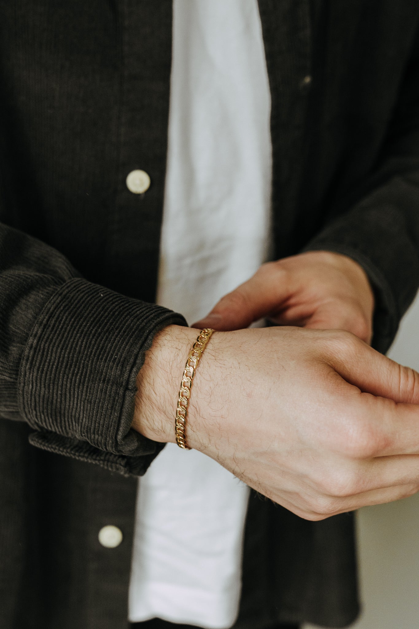 Modern men’s gold bracelet worn layered with casual streetwear and neutral tones