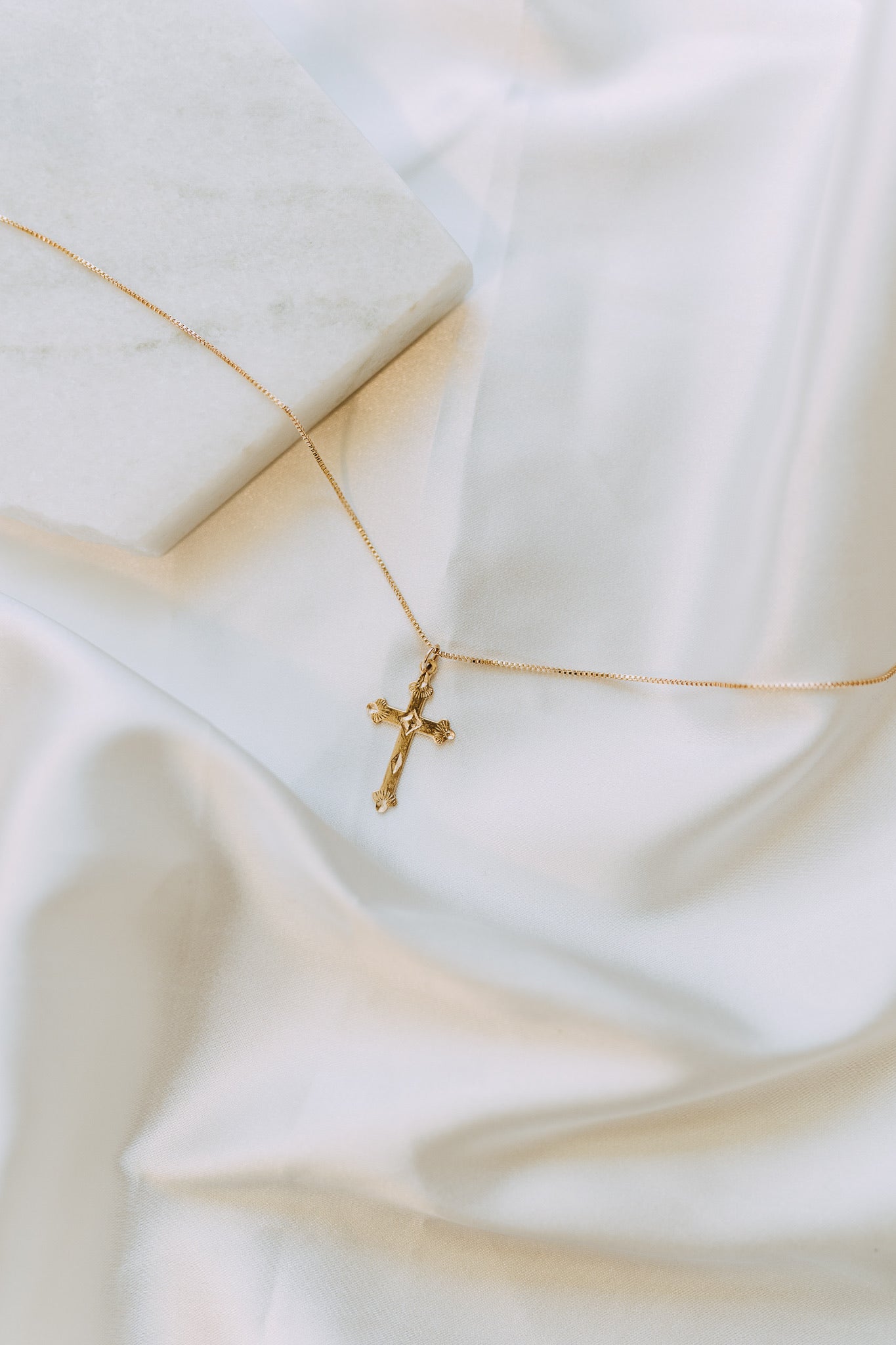 Detailed gold cross pendant on delicate box chain