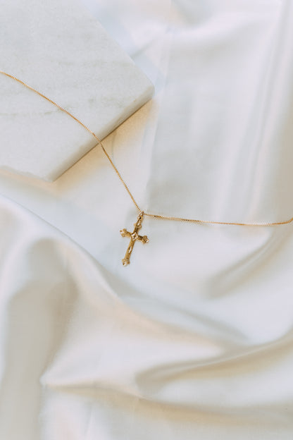 Detailed gold cross pendant on delicate box chain