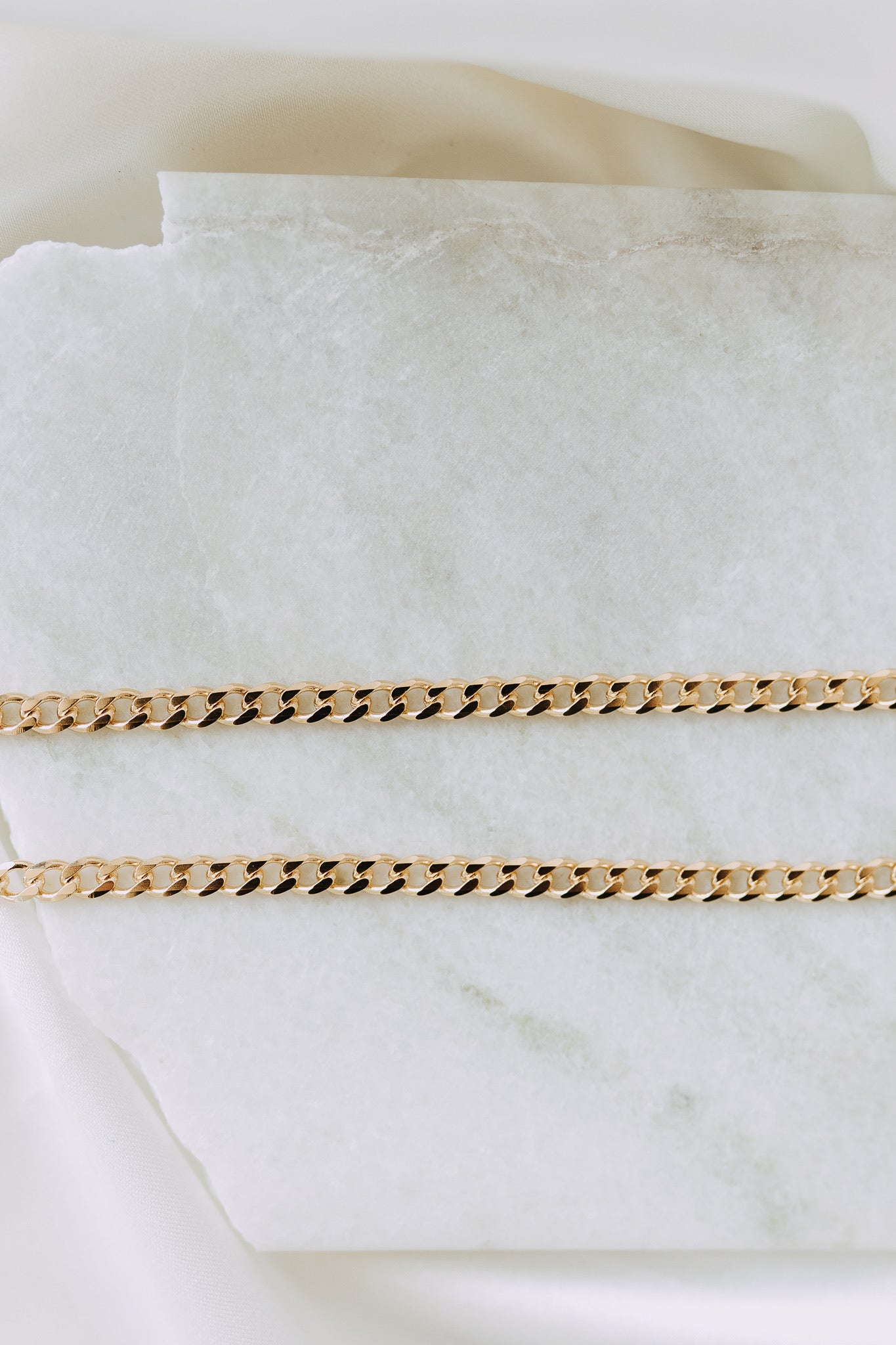 18k gold filled curb chain displayed on marble surface with luxe styling
