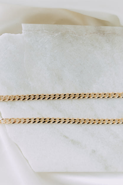 18k gold filled curb chain displayed on marble surface with luxe styling