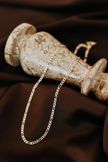 18k gold filled Figaro chain displayed on dark satin fabric