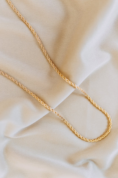 Close-up detail of twisted rope chain necklace with polished gold finish and textured links