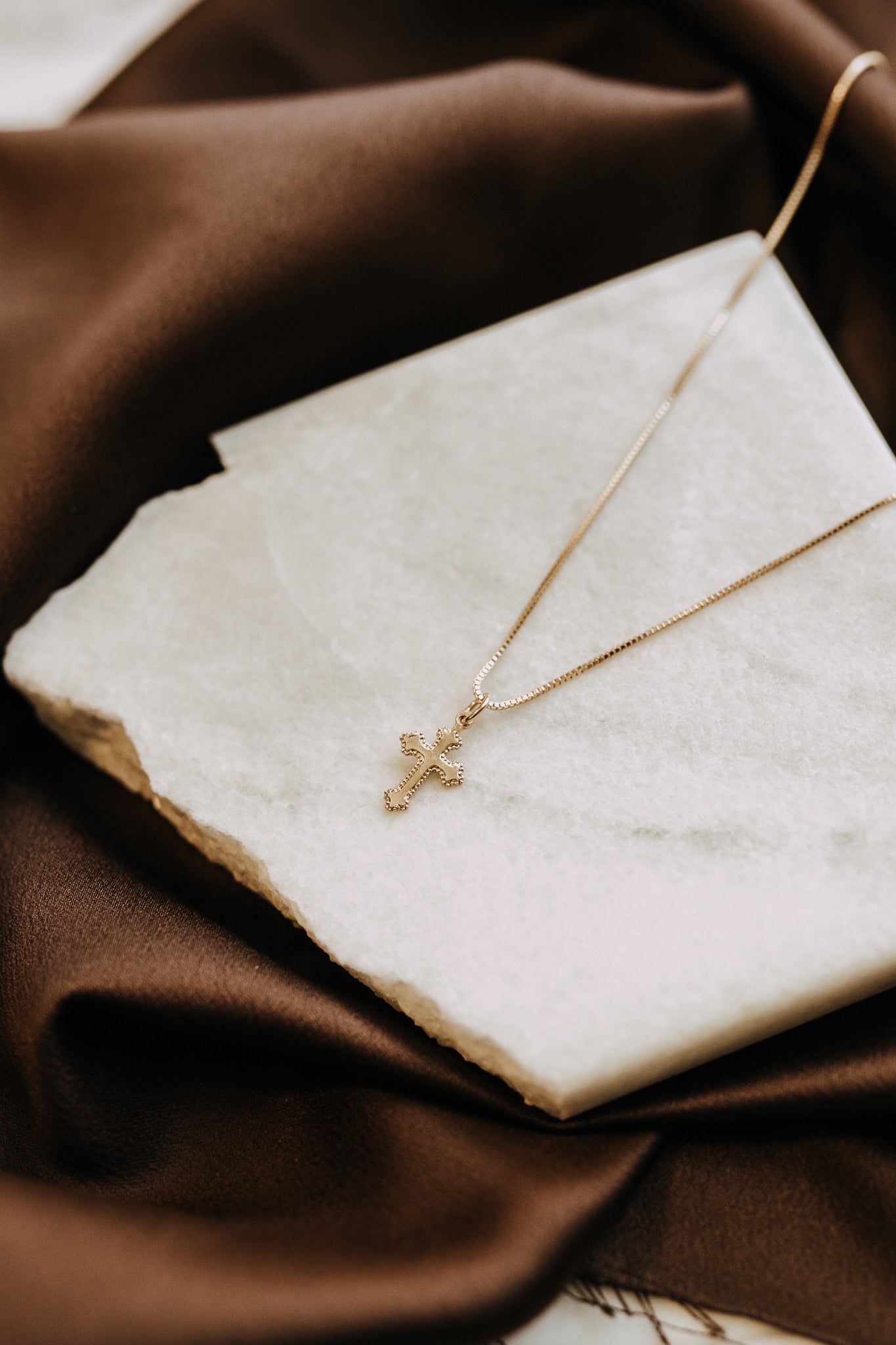 Detailed gold cross pendant necklace close-up