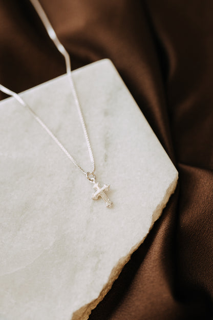 Everyday sterling silver cross necklace photographed on stone tray