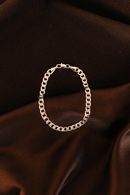 Detailed close-up of men’s curb chain bracelet on dark satin fabric background