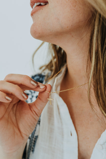 Dainty faith-inspired gold cross necklace styled on model