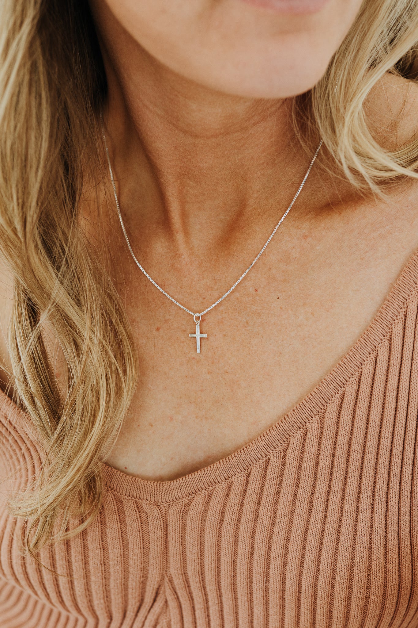 Woman wearing dainty sterling silver cross necklace 