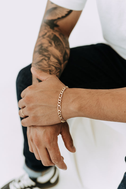Close-up of men’s gold Figaro bracelet with bold 6mm alternating links and modern styling