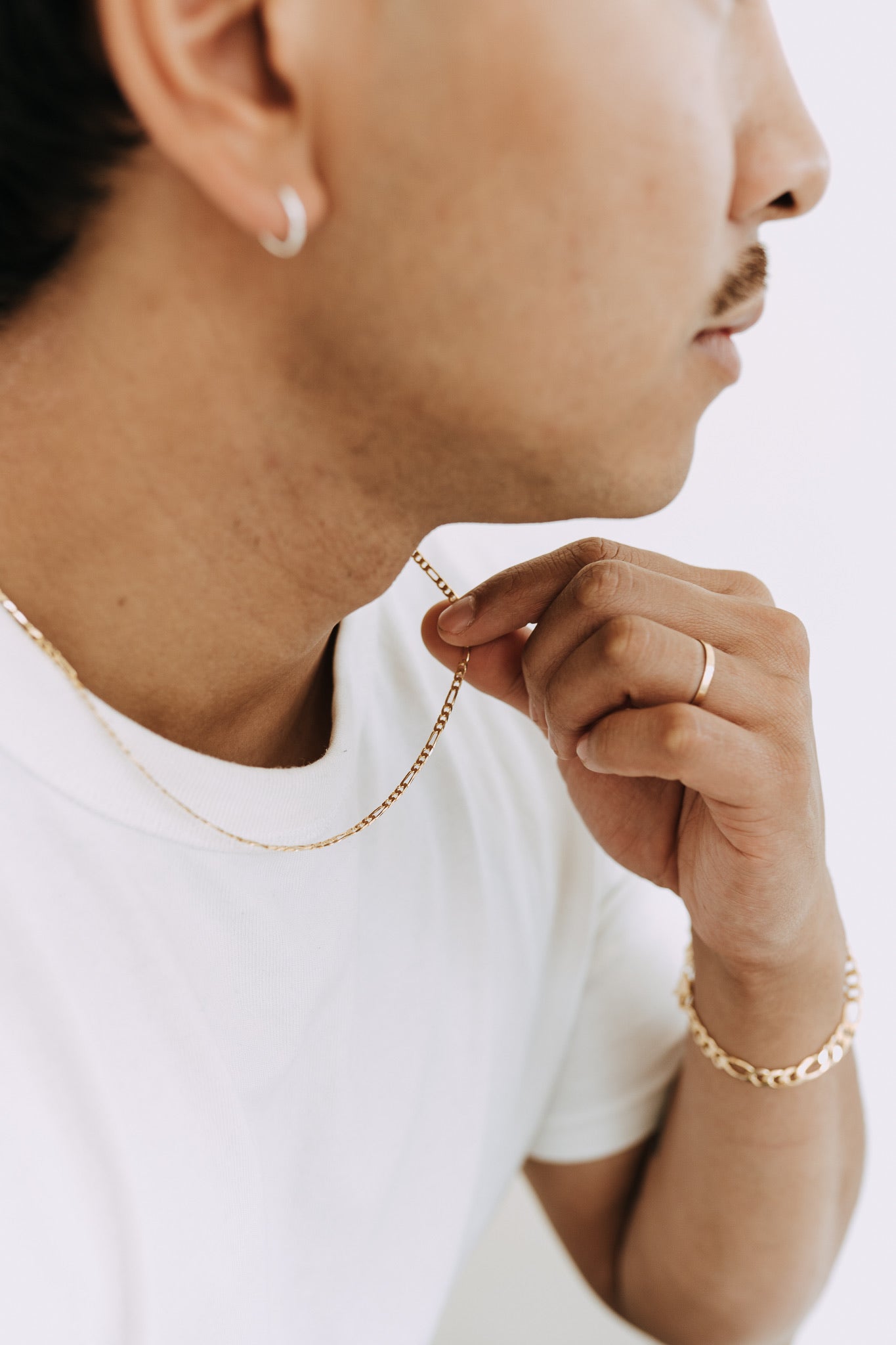 Men’s gold Figaro chain necklace styled with white t-shirt and minimalist jewelry look