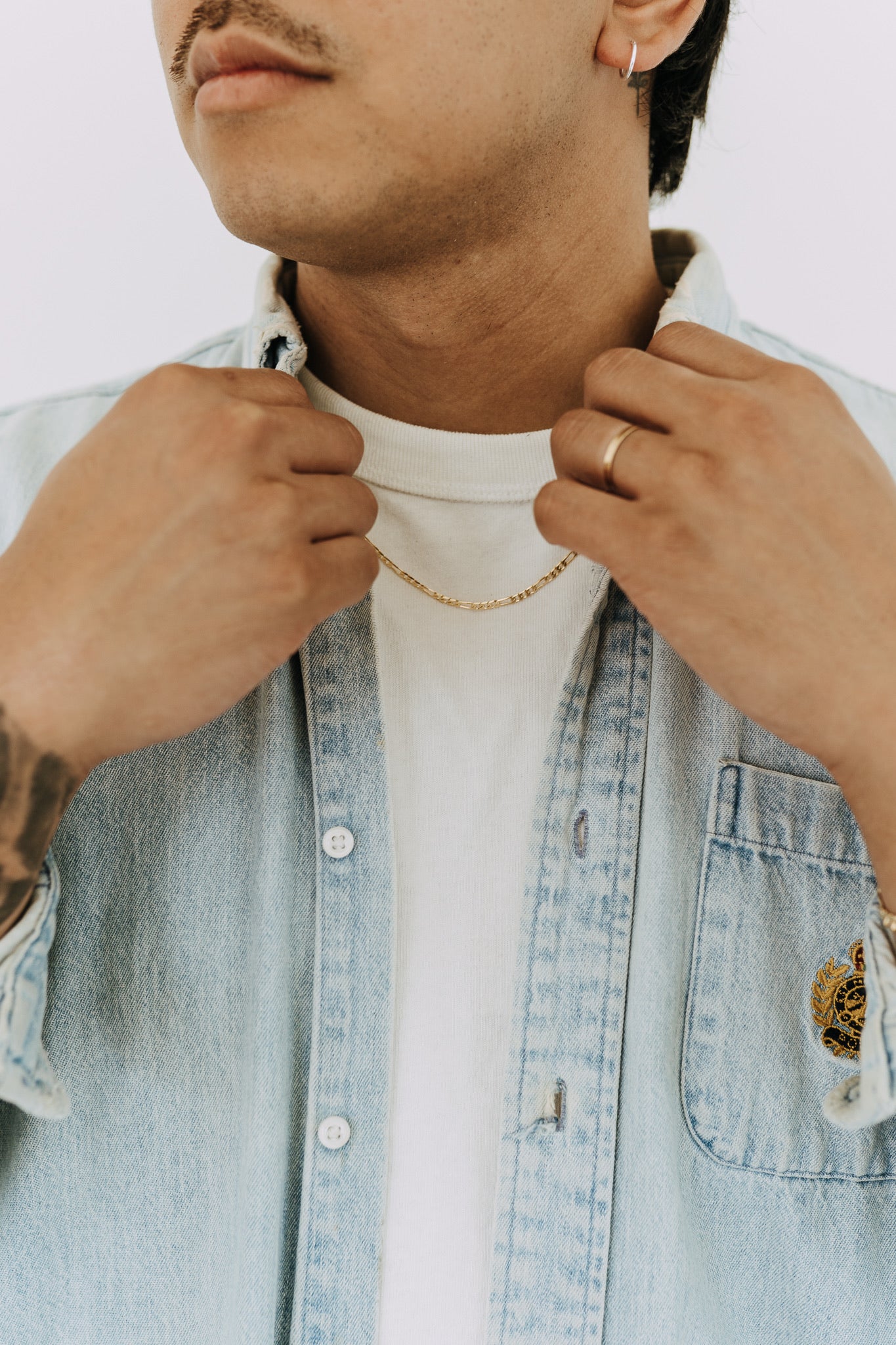 Men’s Figaro chain necklace layered with light denim button-up and white tee