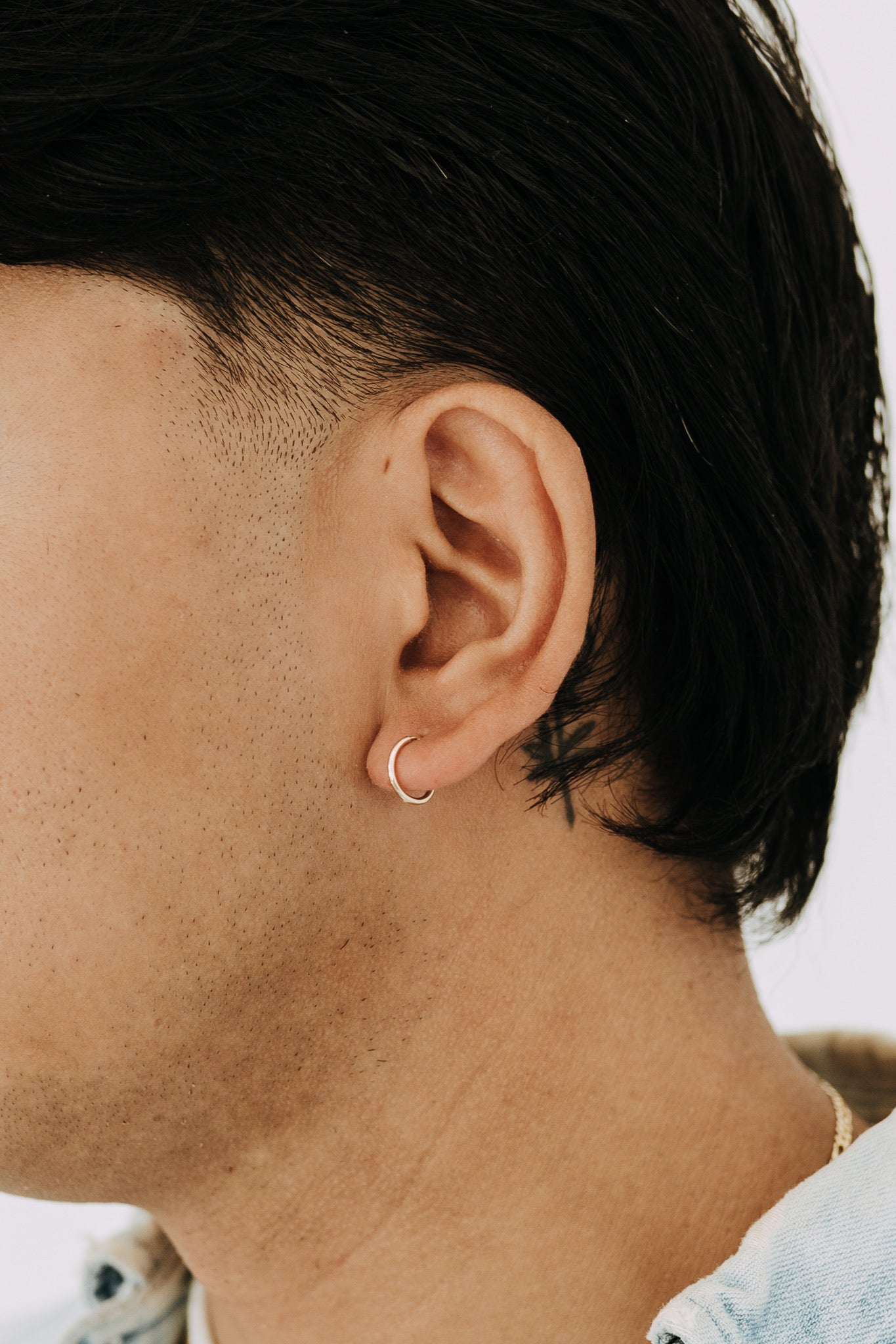 Close-up of men's small gold hoop earring in pierced ear