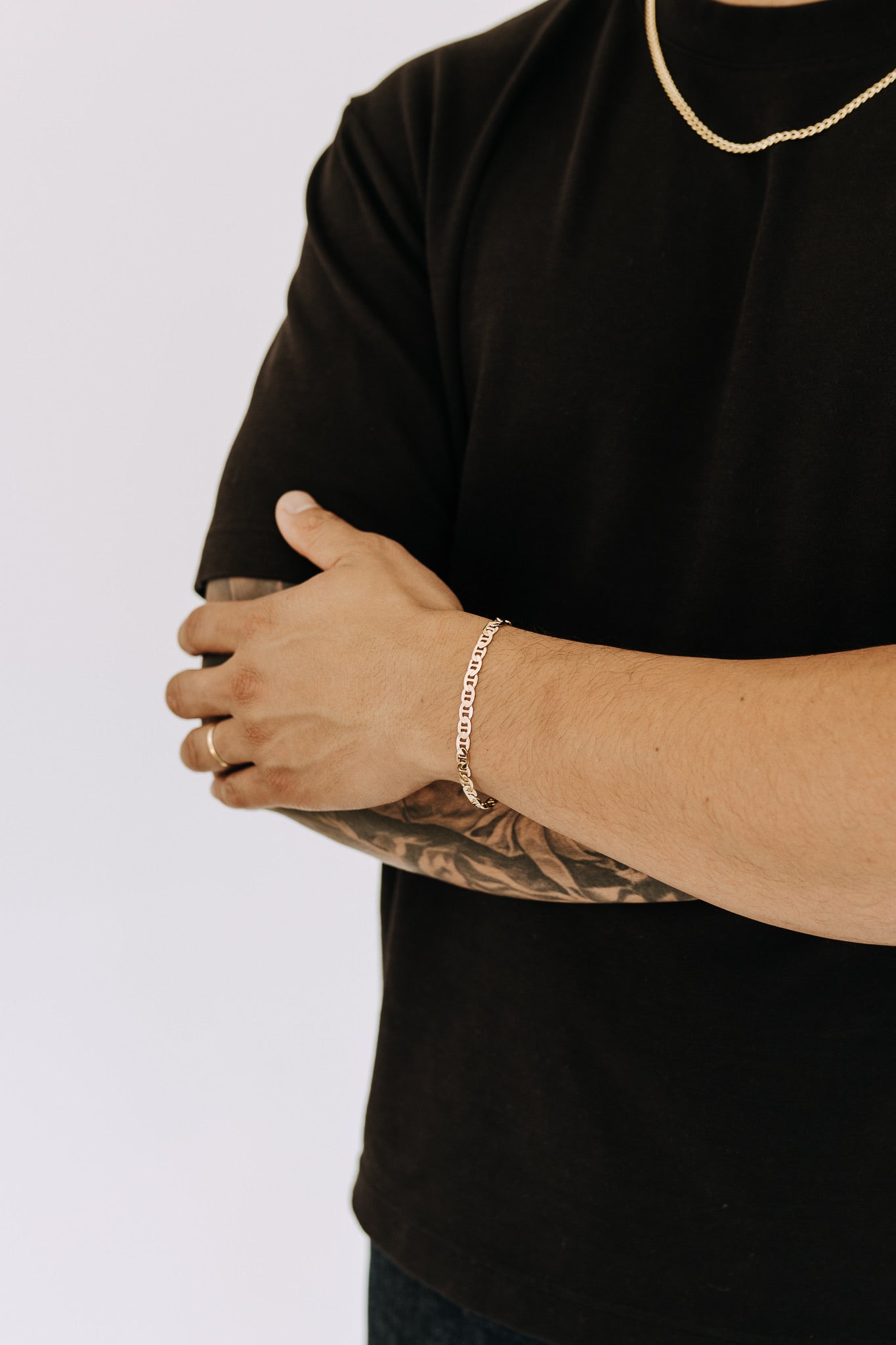 Men’s Roma chain bracelet in polished gold styled with black tee and layered gold chain necklace