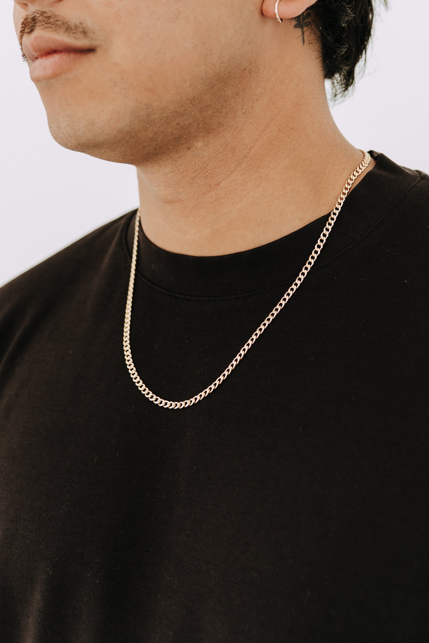 Men’s 4mm gold curb chain necklace styled with black t-shirt and minimalist look