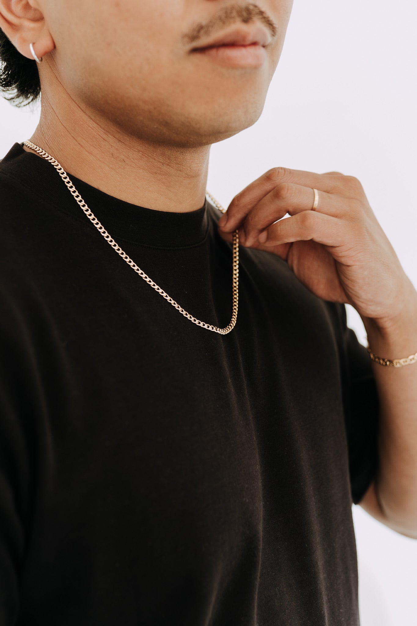 Close-up of man holding gold curb chain necklace with polished flat links