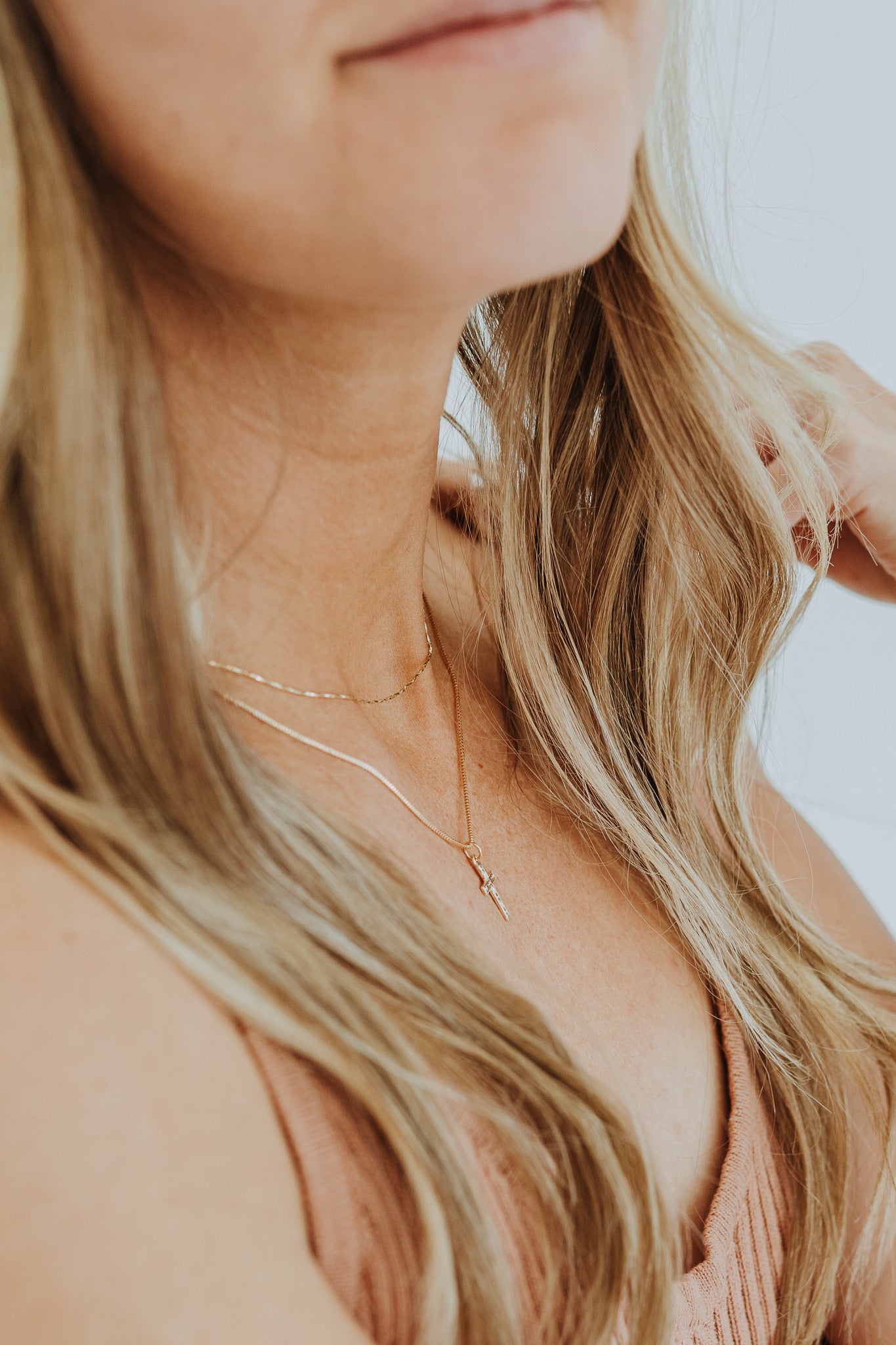 Layered gold necklaces featuring delicate cross charm
